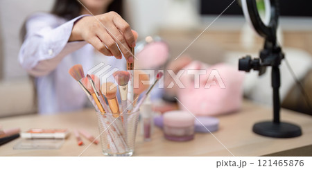 Asian woman selecting makeup brush from collection on table Asian woman selecting makeup brush from collection on table 121465876