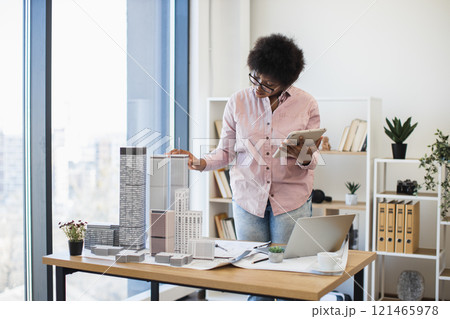 African American woman architect mid-30s develops modern city project using digital tablet office environment. 121465978