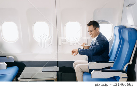 Attractive Asian male passenger of airplane sitting in comfortable seat while working laptop and tablet with mock up area using wireless connection. Attractive Asian male passenger of airplane sitting in comfortable seat while working laptop and tablet with mock up area using wireless connection. 121466663