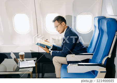 Young Asian executive excels in first class, multitasking with digital tablet, laptop and smartphone. 121466685