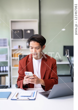 Confident Asian man with a smile standing holding notepad and tablet at the modern office. 121467061