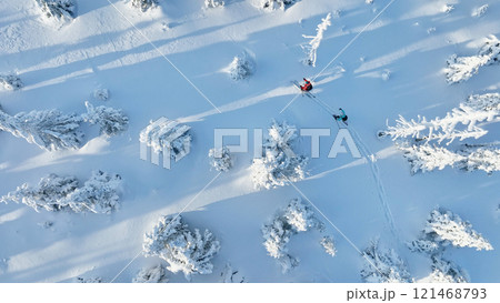 Aerial view of ski touring man and woman with snow shoes crossing winter mountains, fresh snow. Aerial view of ski touring man and woman with snow shoes crossing winter mountains, fresh snow. 121468793