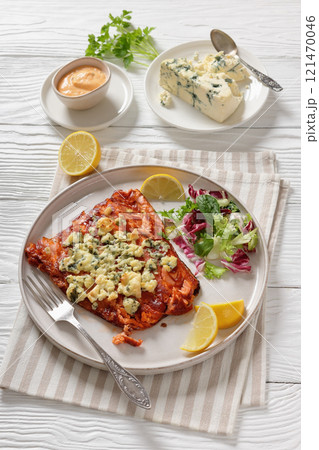baked salmon topped with blue cheese on a plate 121470046