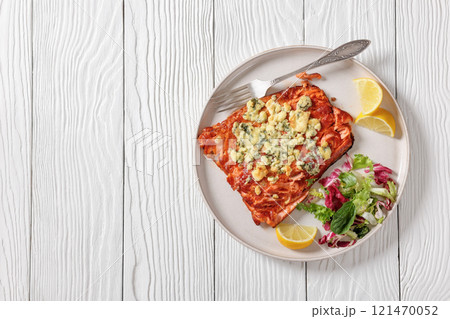 baked salmon topped with blue cheese on a plate 121470052