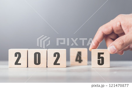 A hand replaces "2024" with "2025" using number blocks, symbolizing the transition into the new year, representing change, progress, and the ongoing passage of time A hand replaces "2024" with "2025" using number blocks, symbolizing the transition into the new year, representing change, progress, and the ongoing passage of time 121470877