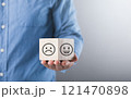 A man holds a wooden block with a smiling face, symbolizing positivity and happiness. This image reflects the concept of embracing joy and maintaining an optimistic outlook A man holds a wooden block with a smiling face, symbolizing positivity and happiness. This image reflects the concept of embracing joy and maintaining an optimistic outlook 121470898