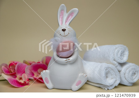 Easter white hare with brown egg on background of orchid flowers white towels 121470939