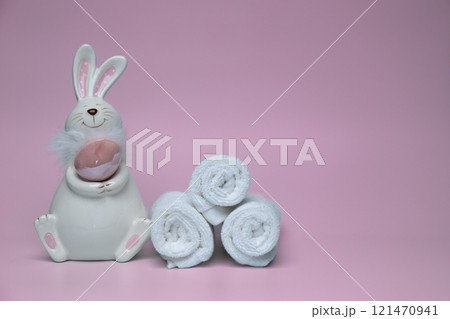 Sculpture of white rabbit with Easter eggs on pink background with white towels Sculpture of white rabbit with Easter eggs on pink background with white towels 121470941