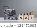 Coins in a miniature shopping cart, wooden blocks labeled VAT, and neatly stacked coins on a table illustrating tax and spending concepts against a gray background Coins in a miniature shopping cart, wooden blocks labeled VAT, and neatly stacked coins on a table illustrating tax and spending concepts against a gray background 121471003