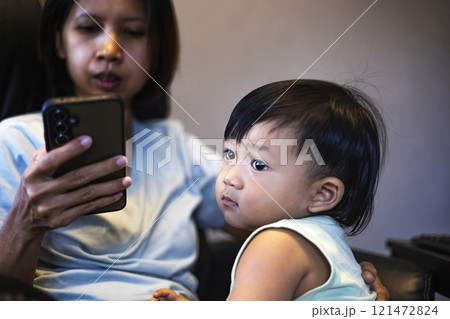 Little boy sitting near his mother working online with smartphone at home. Little boy sitting near his mother working online with smartphone at home. 121472824