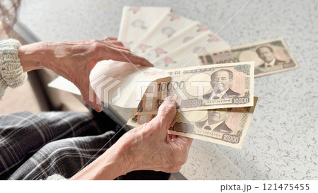 お年玉袋に新1万円札を入れる高齢女性の手元と並べたお年玉袋 お年玉袋に新1万円札を入れる高齢女性の手元と並べたお年玉袋 121475455