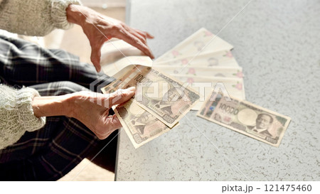 並べたお年玉袋に新1万円札を入れる高齢女性の手元 並べたお年玉袋に新1万円札を入れる高齢女性の手元 121475460
