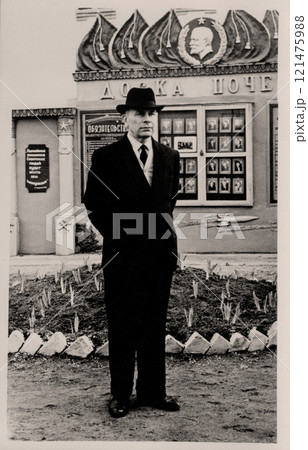 Vintage portrait of an elderly man in the uniform of a USSR railway worker near the honor board. The inscription on the Russian Honor Board. Retro photo from 1960. 121475988