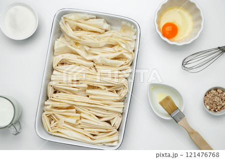 Filo dough in a baking dish near Crinkle Cake butter for buttering 121476768