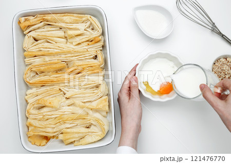 Baked phyllo dough for Crinkle Cake, mixing egg and sugar to make custard Baked phyllo dough for Crinkle Cake, mixing egg and sugar to make custard 121476770