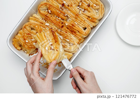 Finished Crinkle Cake made from phyllo dough is cut with a knife Finished Crinkle Cake made from phyllo dough is cut with a knife 121476772