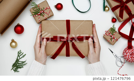 Festive decorations in a cozy holiday setting, womans hands wrapping Christmas gifts 121476796