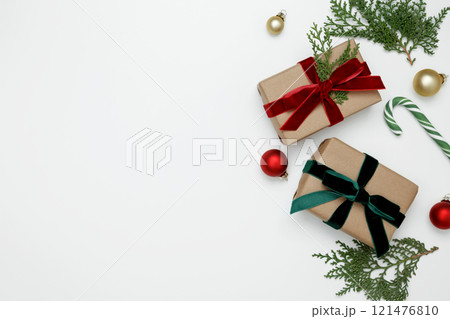 Wrapped Christmas gifts with green thuja branches creating a festive, natural holiday scene Wrapped Christmas gifts with green thuja branches creating a festive, natural holiday scene 121476810