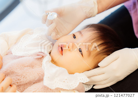 乳児検診を受けて不安顔な乳児 121477027