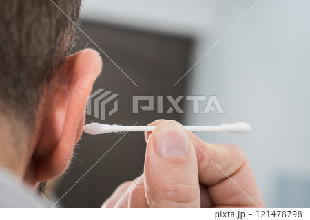 Man removing wax from ear using Q-tip 121478798