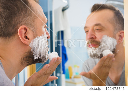 Guy shaving his beard in bathroom Guy shaving his beard in bathroom 121478843