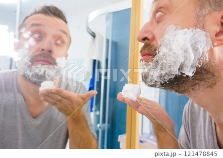 Guy shaving his beard in bathroom 121478845
