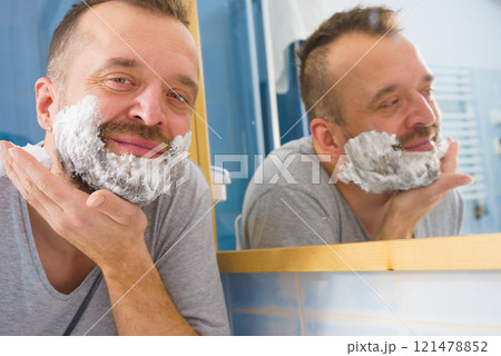 Guy shaving his beard in bathroom 121478852