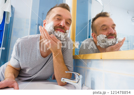 Guy shaving his beard in bathroom Guy shaving his beard in bathroom 121478854