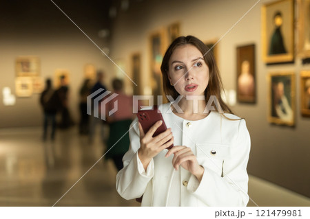 Woman with mobile phone on the background of paintings 121479981