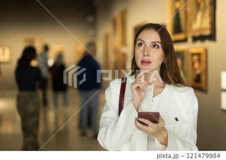 Woman with mobile phone on the background of paintings 121479984