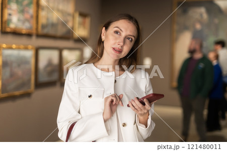 Woman in a Jacket and with a Phone in a Museum of Paintings 121480011