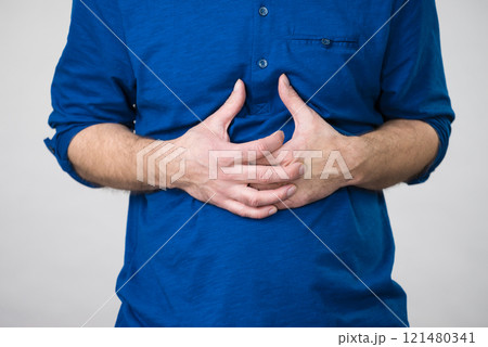 Man having crossed fingers on his stomach 121480341