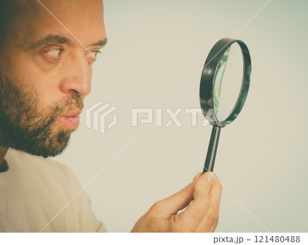 Curious man using magnifying glass 121480488