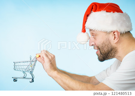 Man in santa hat holds empty shopping cart Man in santa hat holds empty shopping cart 121480513