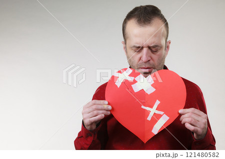 Sad adult man holding broken heart 121480582