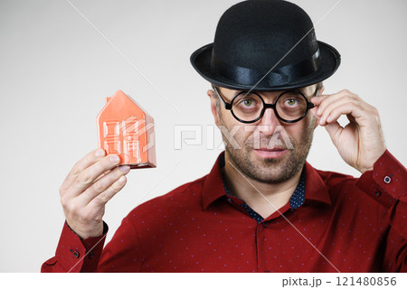 Man wearing funny eyeglasses holding house 121480856