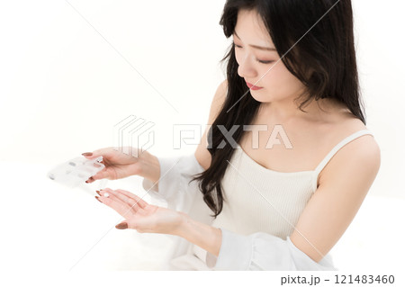 サプリメントケースと錠剤を持つ若い女性 121483460