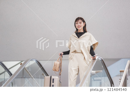 空港に到着しエスカレーターからか降りてくる女性 空港に到着しエスカレーターからか降りてくる女性 121484540