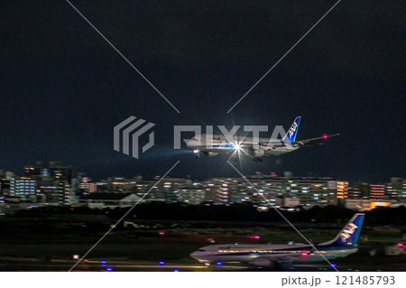 夜の福岡空港へ着陸するANAの飛行機と離陸準備するANAの飛行機 121485793