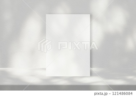 White A4 Paper on Concrete Table with Light Bokeh and Leaves Shadow on Wall 121486084