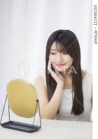 鏡を見て肌を気にする若い女性 121486203