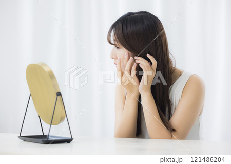 鏡を見て肌を気にする若い女性 121486204