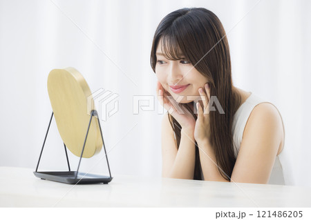 鏡を見て肌を気にする若い女性 121486205
