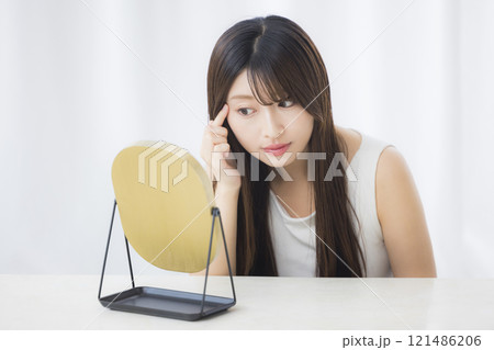 鏡を見て肌を気にする若い女性 121486206