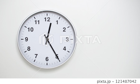 Minimalist White Clock with Silver Frame Striking 12.25/00.25 on White Background. Perfect for Time Management and Corporate Campaigns Minimalist White Clock with Silver Frame Striking 12.25/00.25 on White Background. Perfect for Time Management and Corporate Campaigns 121487042