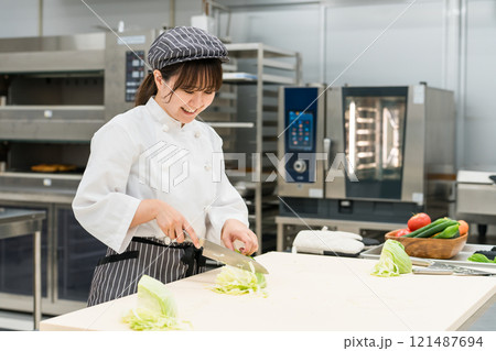 厨房でキャベツを切る調理スタッフの女性 121487694