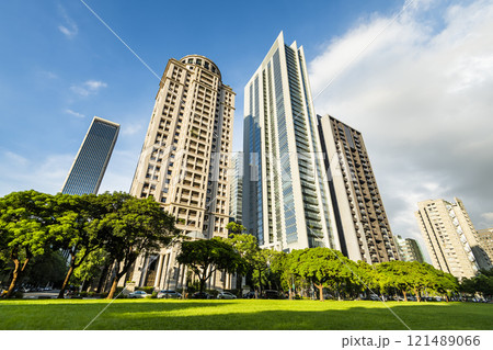 Low-angle view of green park space and modern buildings on both sides in downtown Taichung, Taiwan, It is near the National Taichung Theater. Low-angle view of green park space and modern buildings on both sides in downtown Taichung, Taiwan, It is near the National Taichung Theater. 121489066