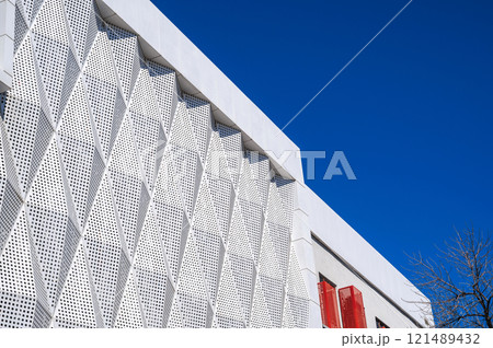 facade of modern futuristic building covered with geometric metal panels on background on the sky 121489432