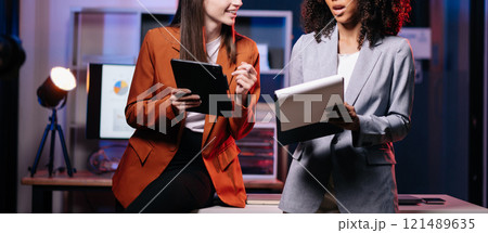 Kind leader executive manager share and discuss business solutions plan ideas on tablet with African female marketing manager. neon light in dark time. 121489635