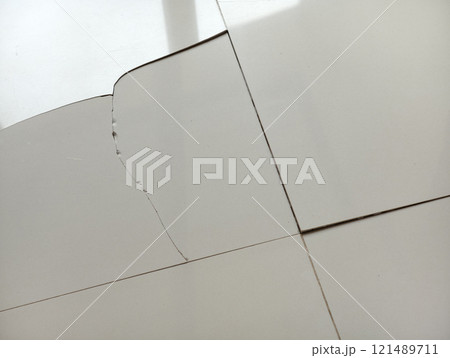 Cracked and damaged floor tiles inside a house, showing visible wear and deterioration. 121489711